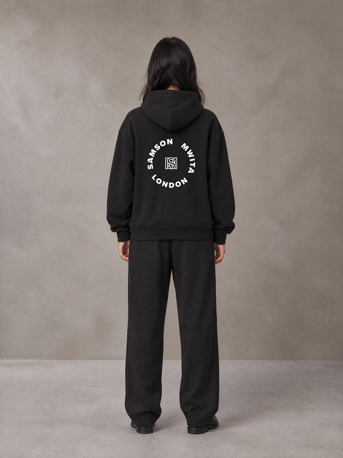 Model wearing the SM London Hoodie and SM London Sweatpants in Midnight Black, rear view.