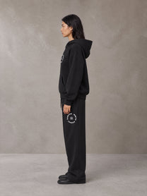 Model wearing the SM London Hoodie and SM London Sweatpants in Midnight Black, side profile.