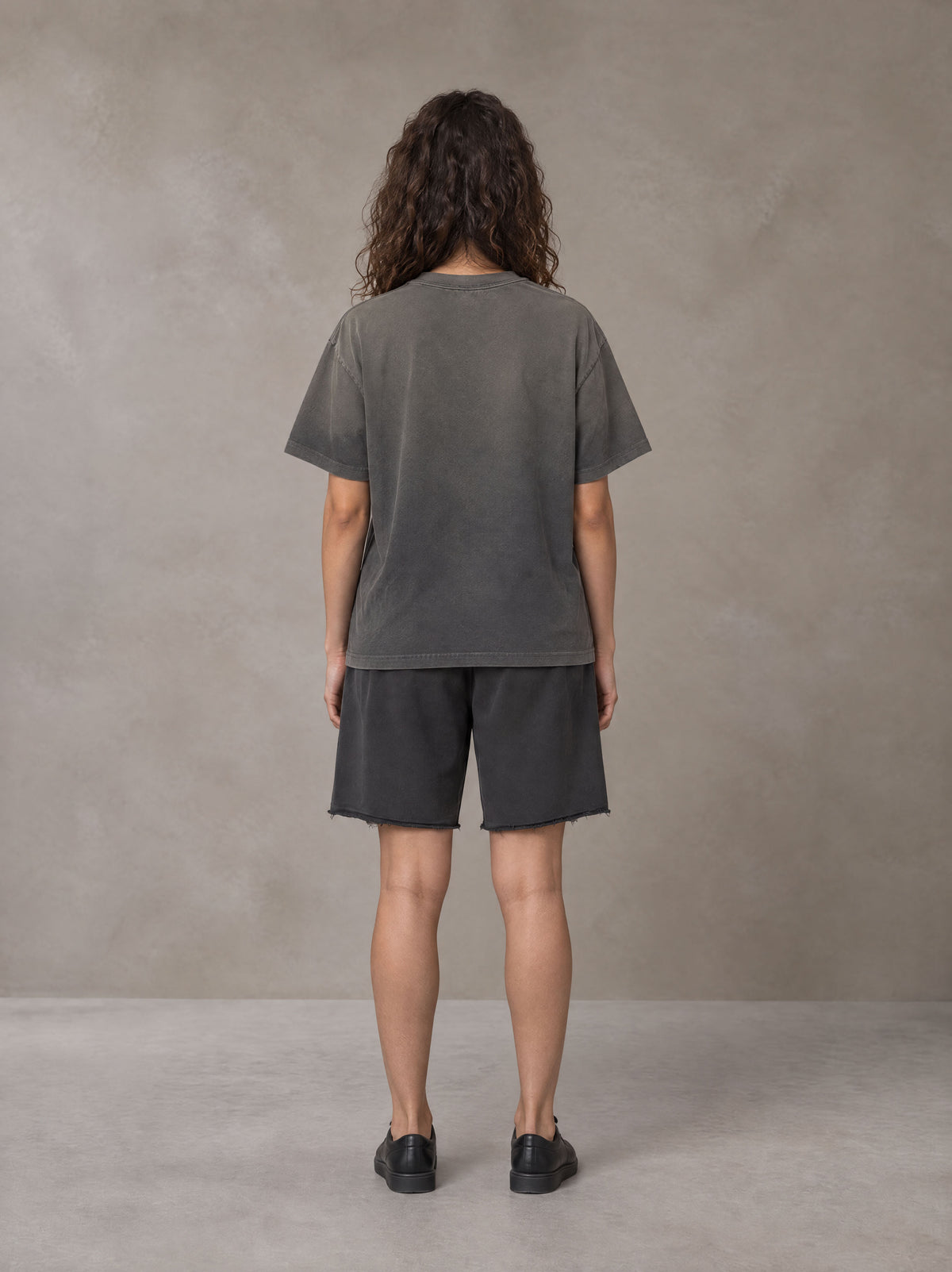 Model wearing the SM Vintage Washed T-shirt and SM Vintage Washed Shorts in Deep Charcoal, rear view.
