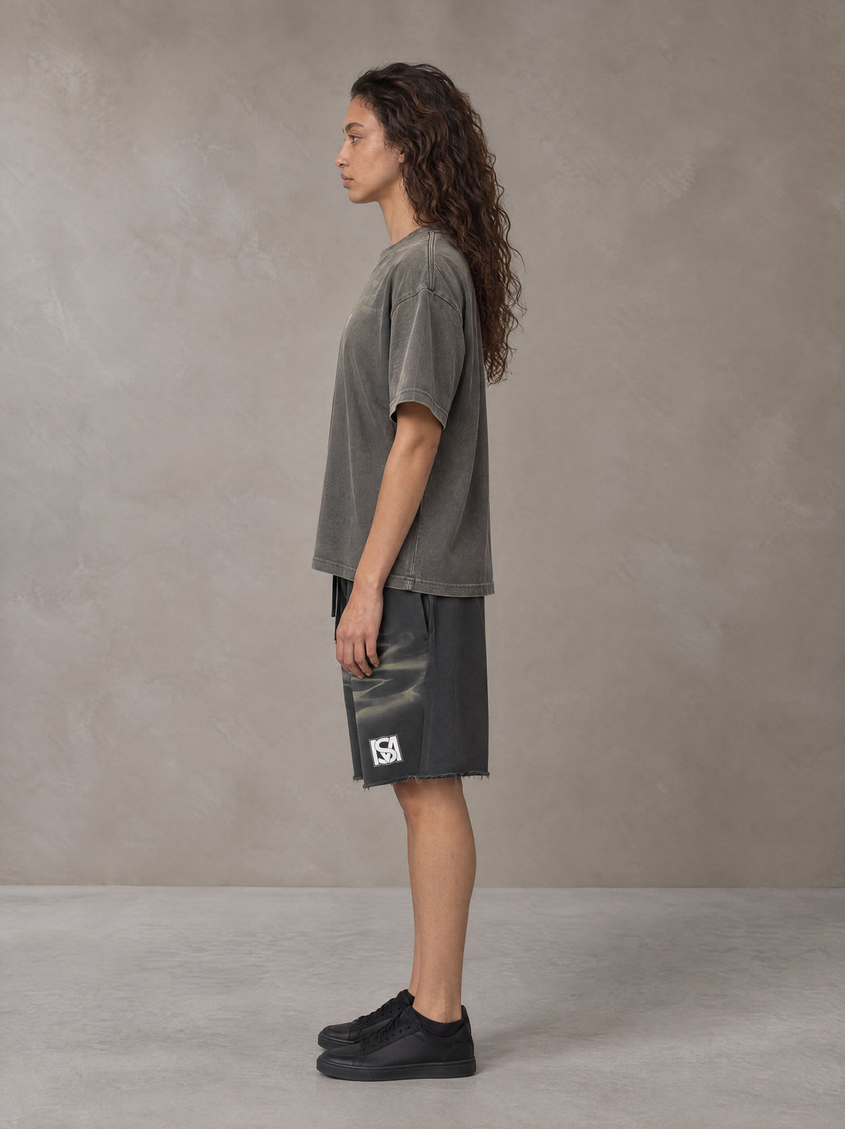 Model wearing the SM Vintage Washed T-shirt and SM Vintage Washed Shorts in Deep Charcoal, side profile.