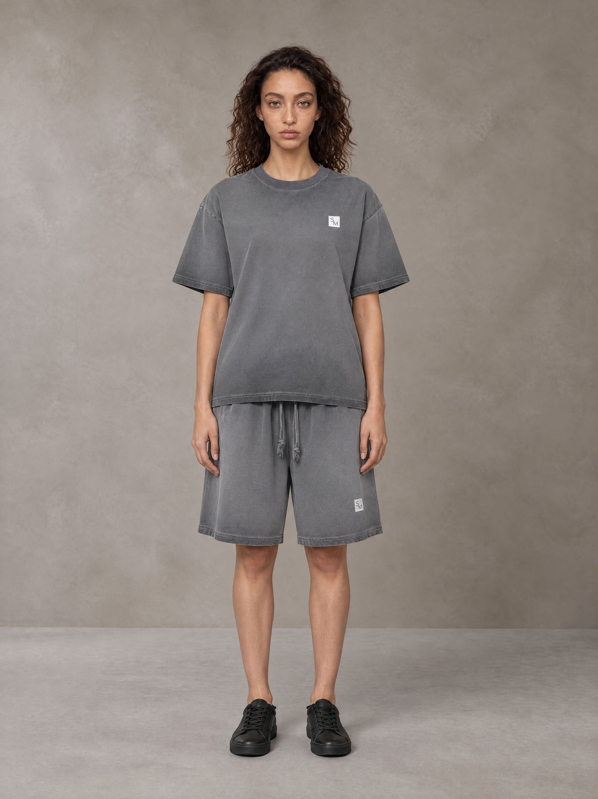 Model wearing the SM Sig. Reverse Dyed T-shirt and SM Sig. Reverse Dyed Shorts in Deep Charcoal, front view.