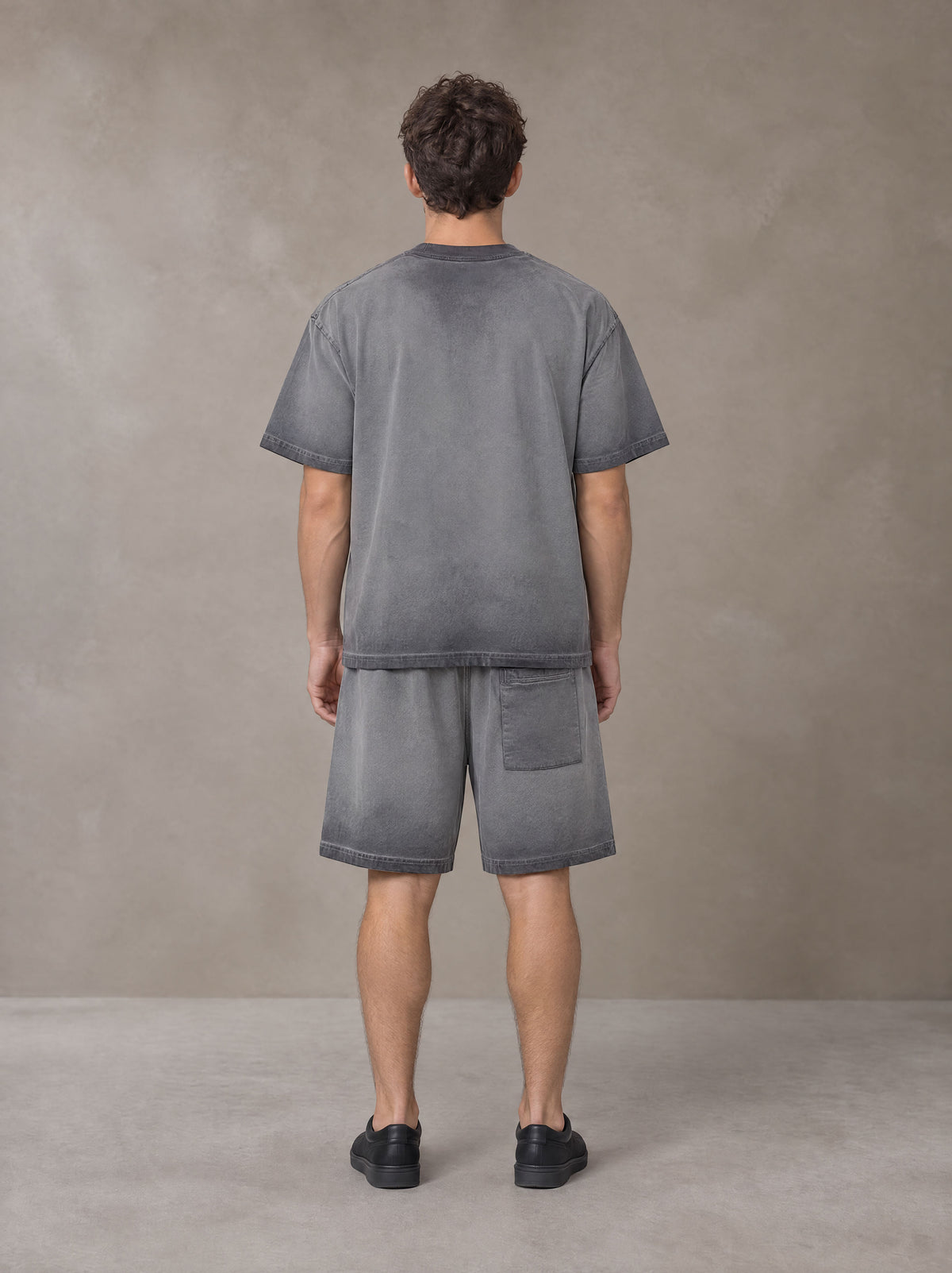 Model wearing the SM Sig. Reverse Dyed T-shirt and SM Sig. Reverse Dyed Shorts in Deep Charcoal, rear view.