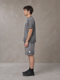 Model wearing the SM Sig. Reverse Dyed T-shirt and SM Sig. Reverse Dyed Shorts in Deep Charcoal, side profile.