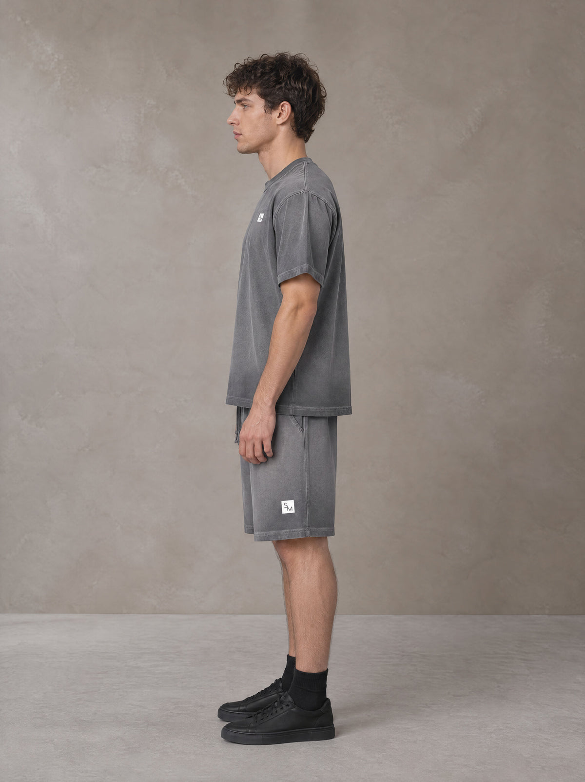 Model wearing the SM Sig. Reverse Dyed T-shirt and SM Sig. Reverse Dyed Shorts in Deep Charcoal, side profile.