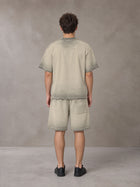 Model wearing the SM Sig. Reverse Dyed T-shirt and SM Sig. Reverse Dyed Shorts in Fine Sand, rear view.
