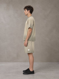 Model wearing the SM Sig. Reverse Dyed T-shirt and SM Sig. Reverse Dyed Shorts in Fine Sand, side profile.