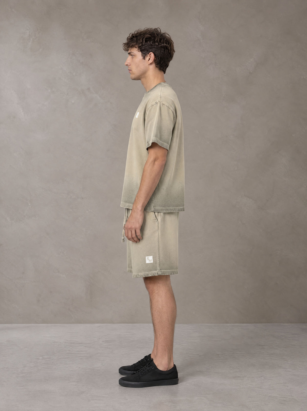 Model wearing the SM Sig. Reverse Dyed T-shirt and SM Sig. Reverse Dyed Shorts in Fine Sand, side profile.