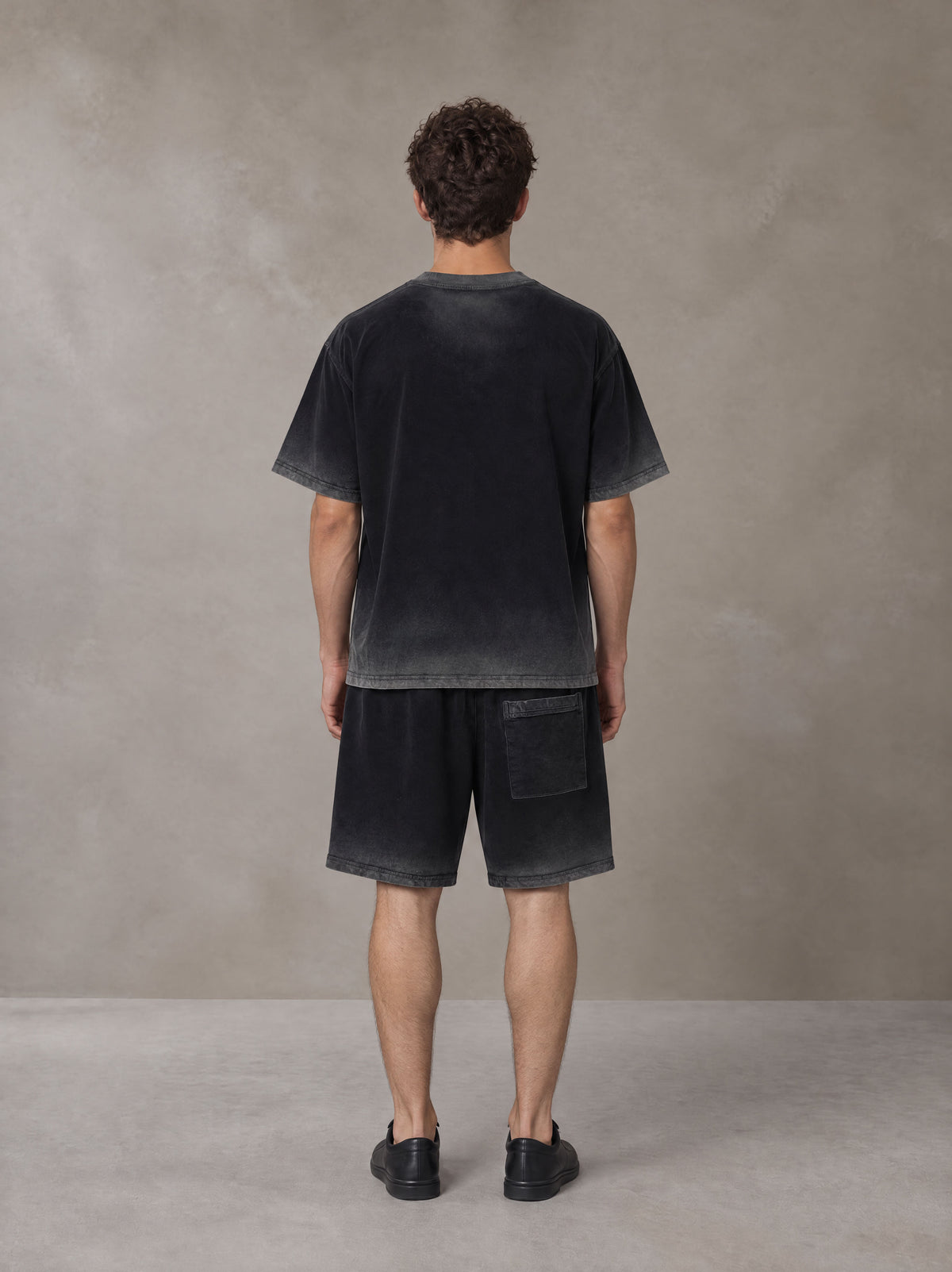 Model wearing the SM Sig. Reverse Dyed T-shirt and SM Sig. Reverse Dyed Shorts in Midnight Black, rear view.