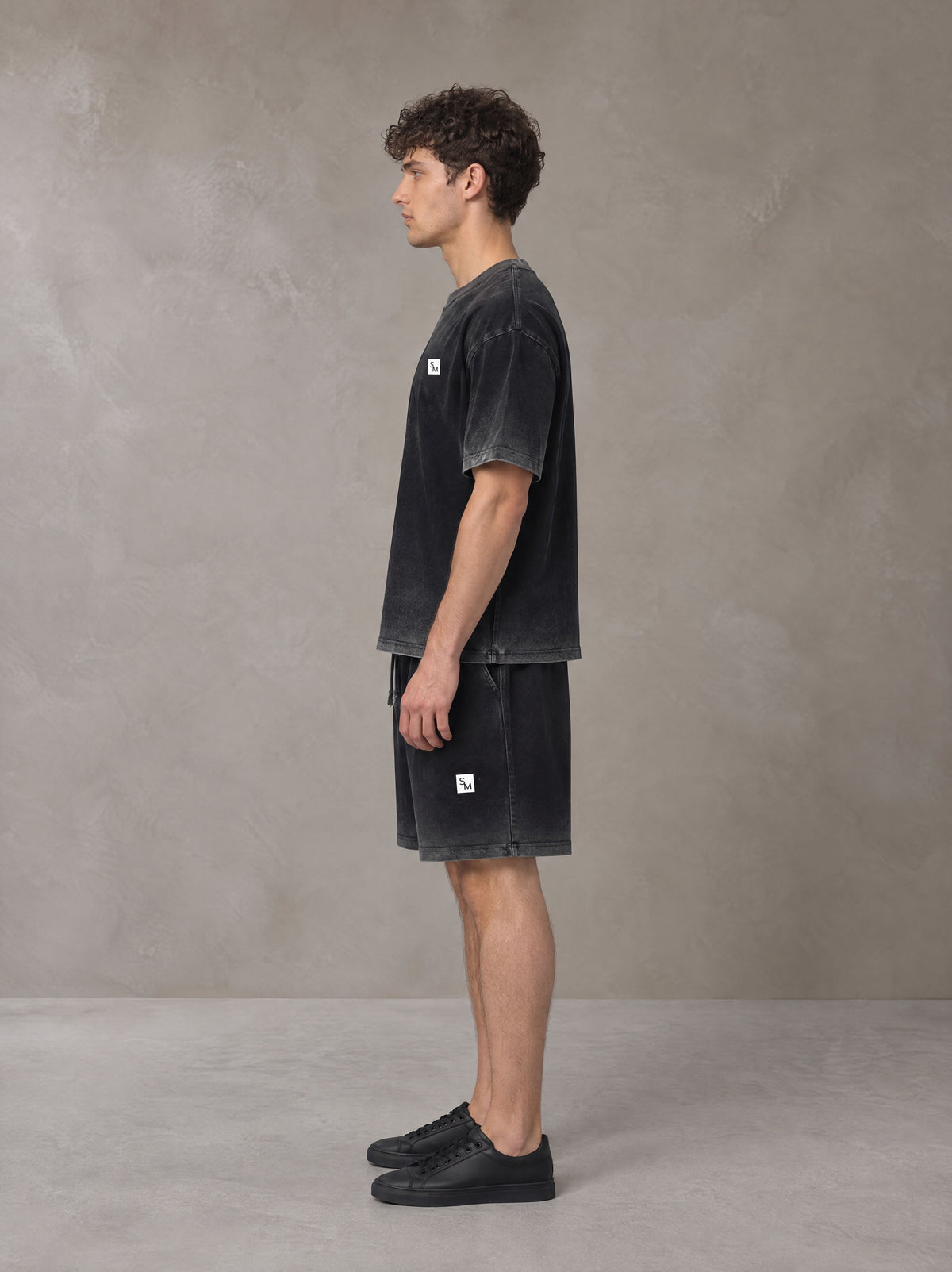 Model wearing the SM Sig. Reverse Dyed T-shirt and SM Sig. Reverse Dyed Shorts in Midnight Black, side profile.