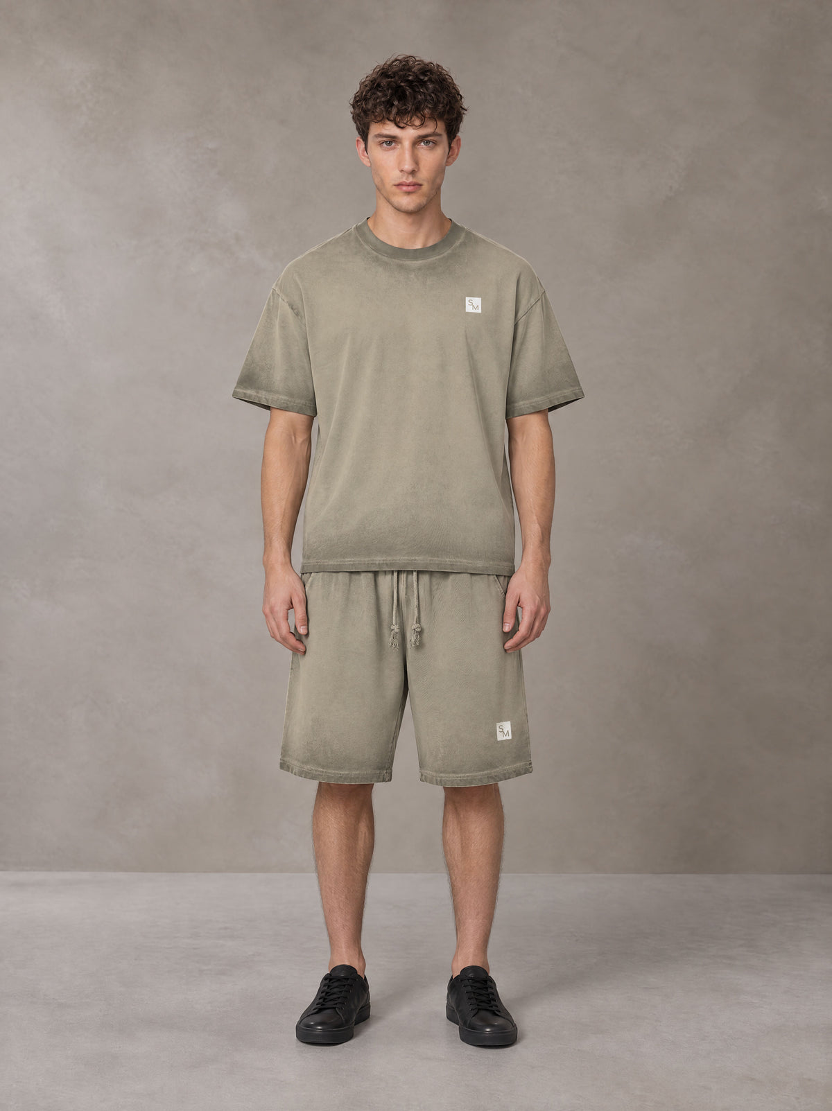Model wearing the SM Sig. Reverse Dyed T-shirt and SM Sig. Reverse Dyed Shorts in Stone Grey, front view.