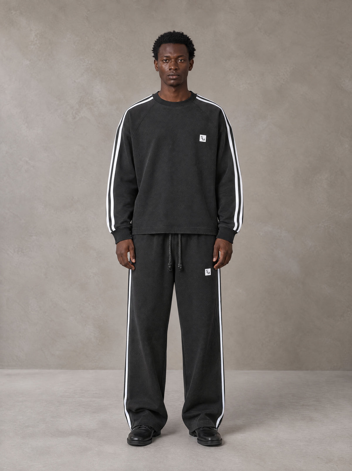Model wearing the SM Sig. Snow Line Sweatshirt and SM Sig. Snow Line Sweatpants in Midnight Black, front view.