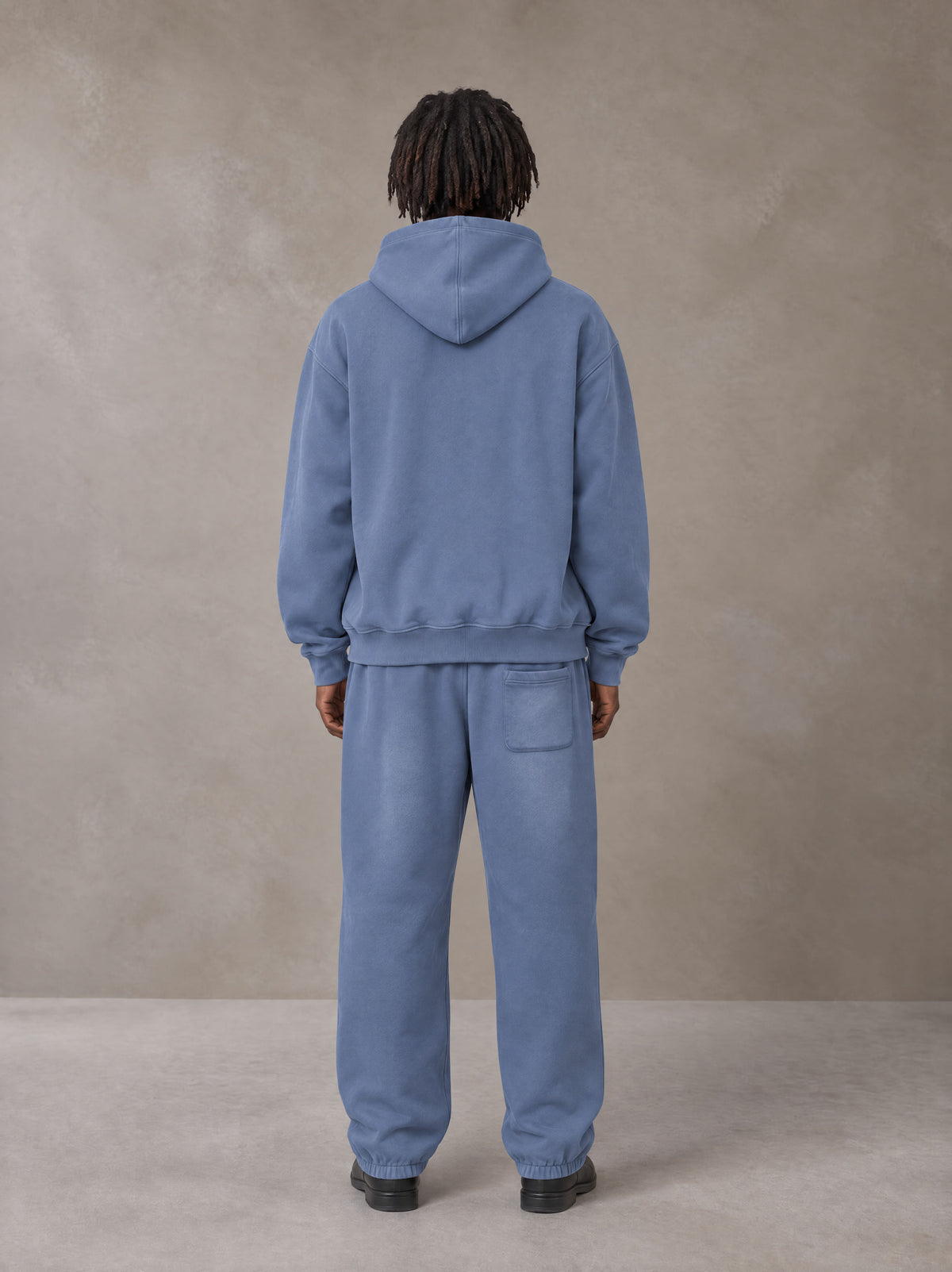 Model wearing the SM Sunfade Fleeced Hoodie and SM Sunfade Fleeced Sweatpants in Deep Denim, rear view.