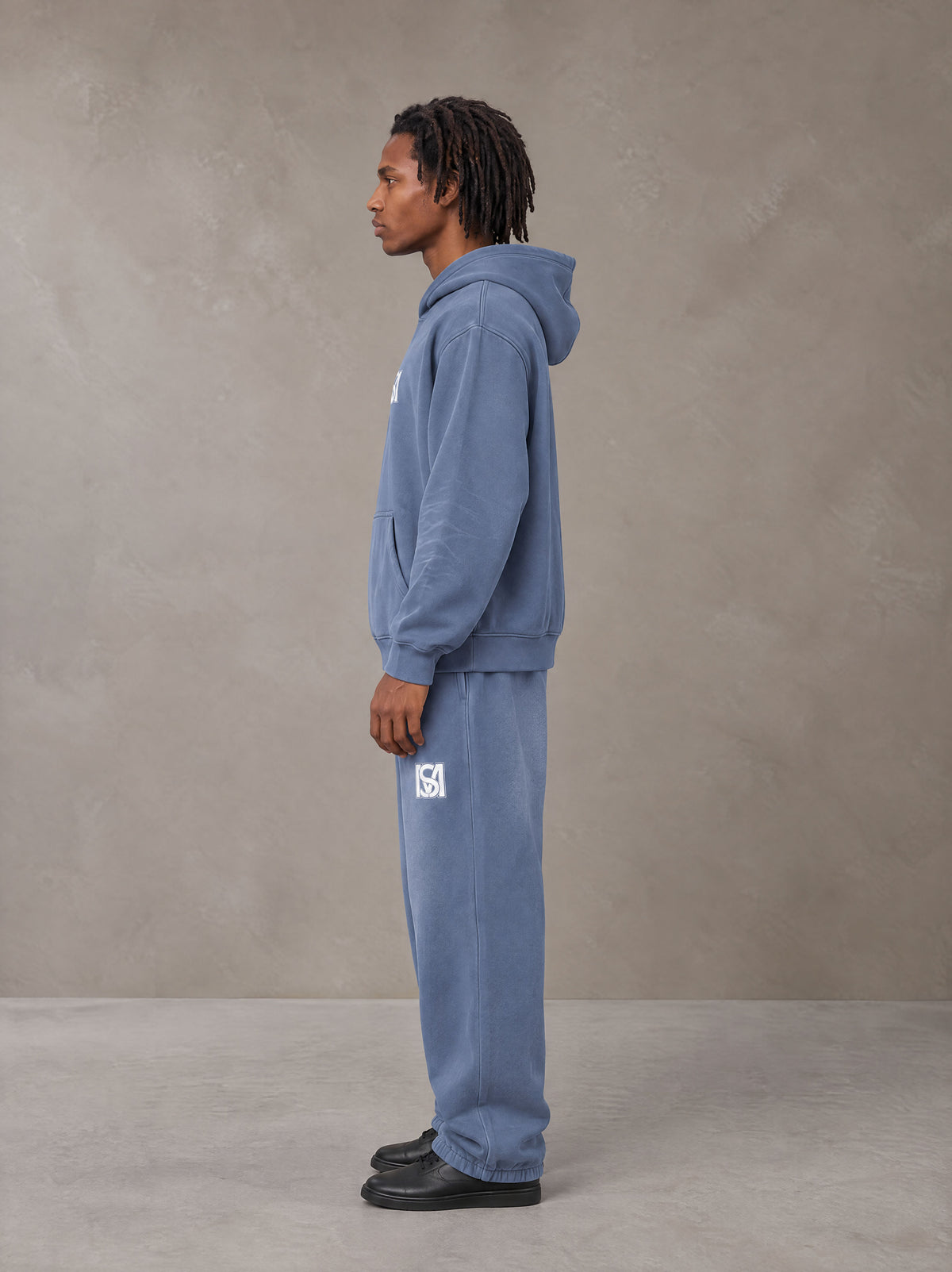 Model wearing the SM Sunfade Fleeced Hoodie and SM Sunfade Fleeced Sweatpants in Deep Denim, side profile.