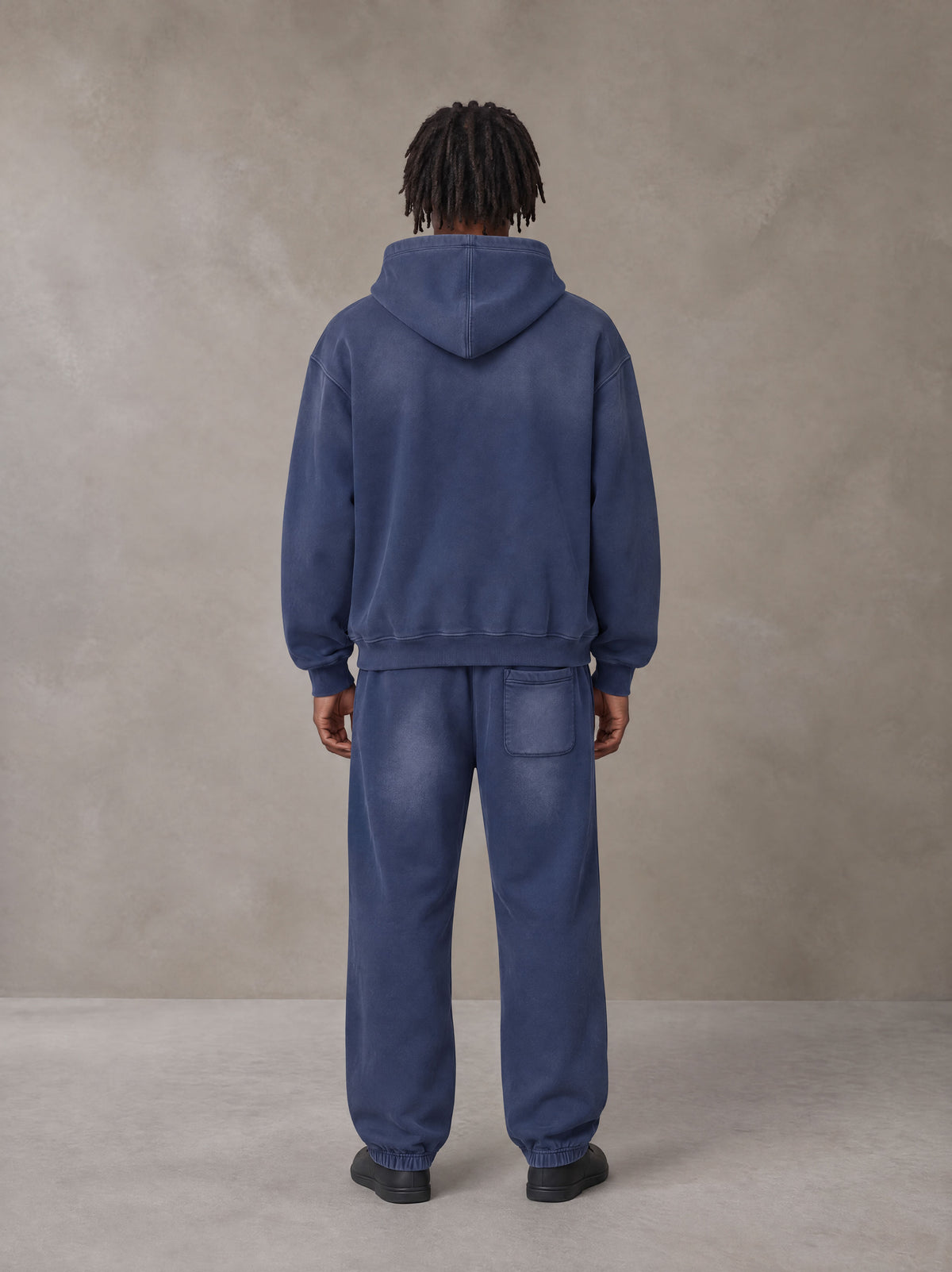Model wearing the SM Sunfade Fleeced Hoodie and SM Sunfade Fleeced Sweatpants in Oxford Navy, rear view.