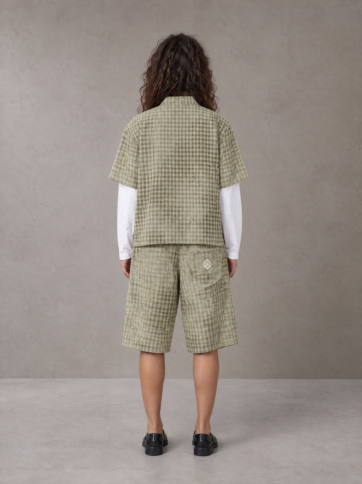 Model wearing the SM Eternal Fleur Mirage Shirt and SM Eternal Fleur Mirage Shorts in Moss, rear view.