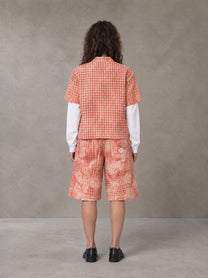 Model wearing the SM Eternal Fleur Mirage Shirt and SM Eternal Fleur Mirage Shorts in Persimmon, rear view.