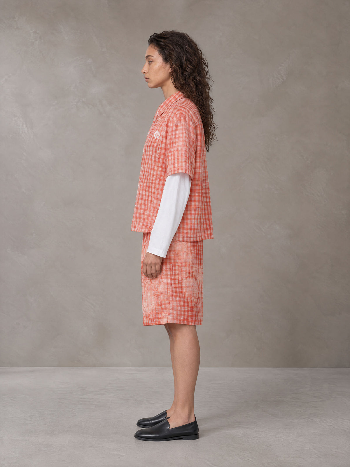 Model wearing the SM Eternal Fleur Mirage Shirt and SM Eternal Fleur Mirage Shorts in Persimmon, side profile.