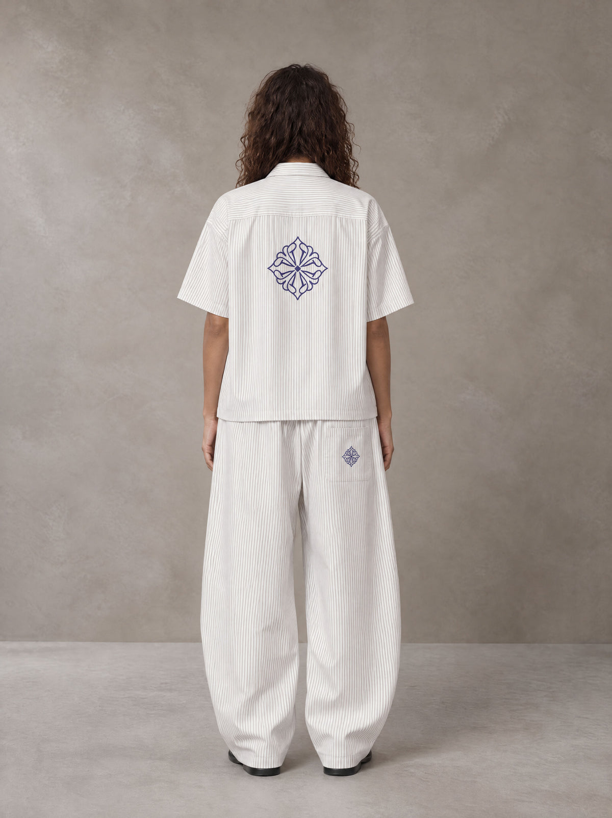 Model wearing the SM The Fabric Of Self Shirt and SM The Fabric Of Self Trousers in Ivory White, rear view.