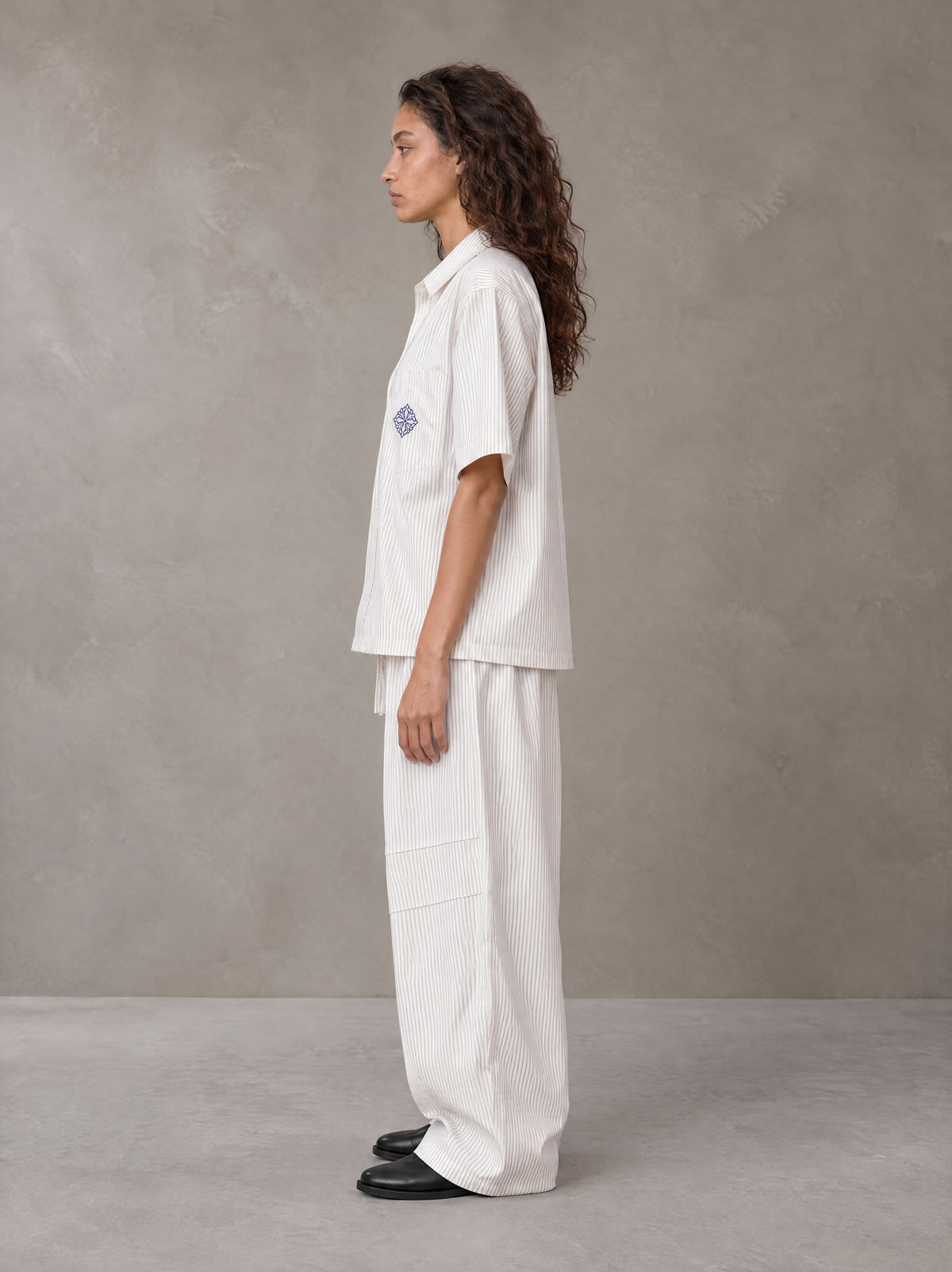 Model wearing the SM The Fabric Of Self Shirt and SM The Fabric Of Self Trousers in Ivory White, side profile.