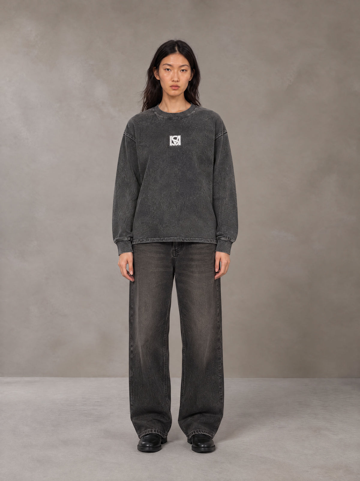 Model wearing the SM Acid Wash Long Sleeve T-shirt in Deep Charcoal, front view.