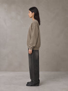 Model wearing the SM Acid Wash Sweatshirt in Coffee Grey, side profile.