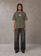 Model wearing the SM Acid Wash T-shirt in Alpine Green, front view.