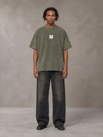 Model wearing the SM Acid Wash T-shirt in Alpine Green, front view.