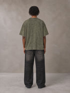 Model wearing the SM Acid Wash T-shirt in Alpine Green, rear view.