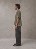 Model wearing the SM Acid Wash T-shirt in Alpine Green, side profile.