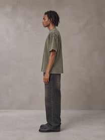 Model wearing the SM Acid Wash T-shirt in Alpine Green, side profile.