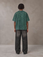 Model wearing the SM Acid Wash T-shirt in Dark Green, rear view.