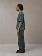 Model wearing the SM Acid Wash T-shirt in Dark Green, side profile.