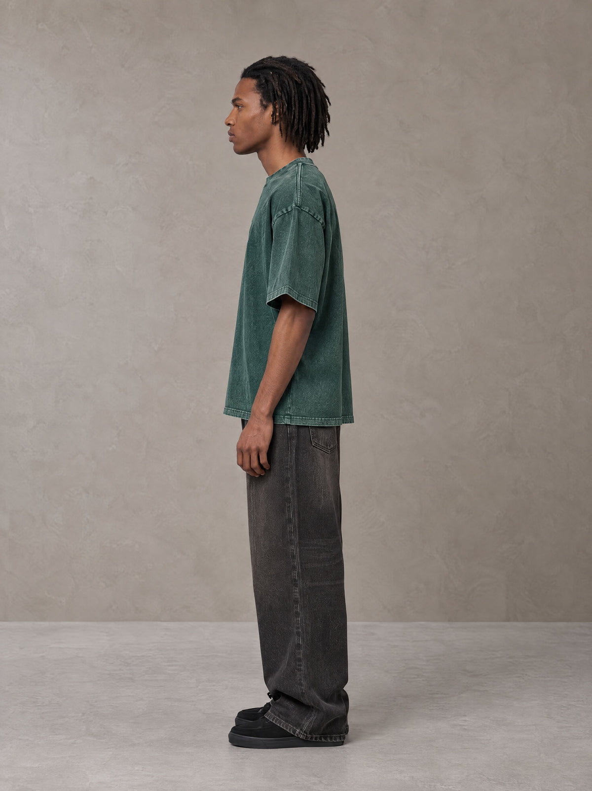 Model wearing the SM Acid Wash T-shirt in Dark Green, side profile.
