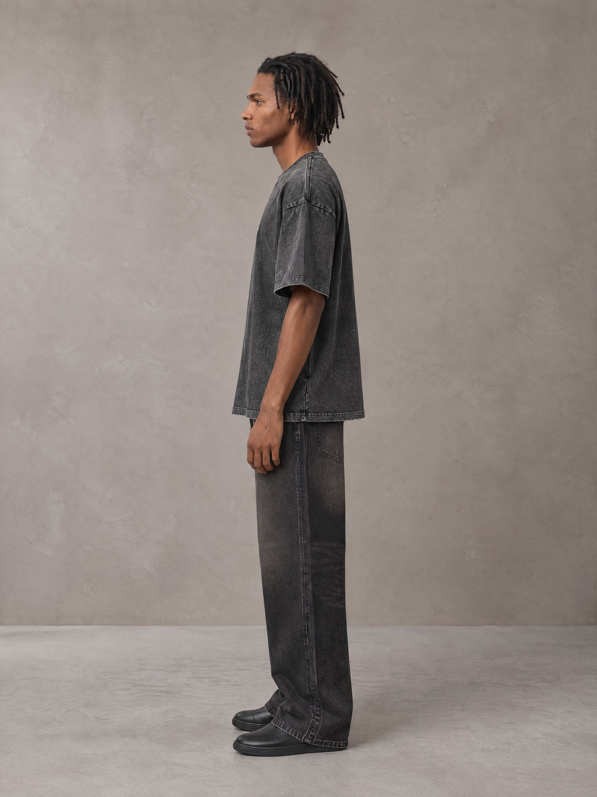 Model wearing the SM Acid Wash T-shirt in Deep Charcoal, side profile.