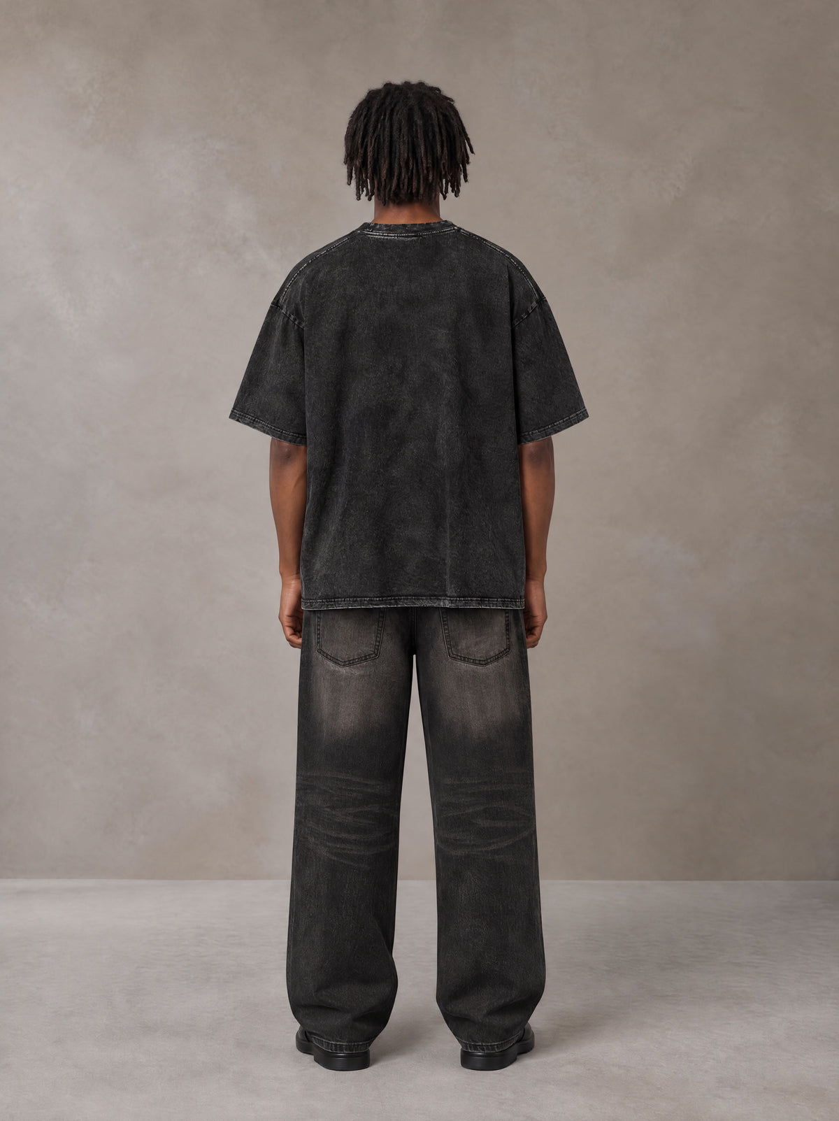 Model wearing the SM Acid Wash T-shirt in Midnight Black, rear view.