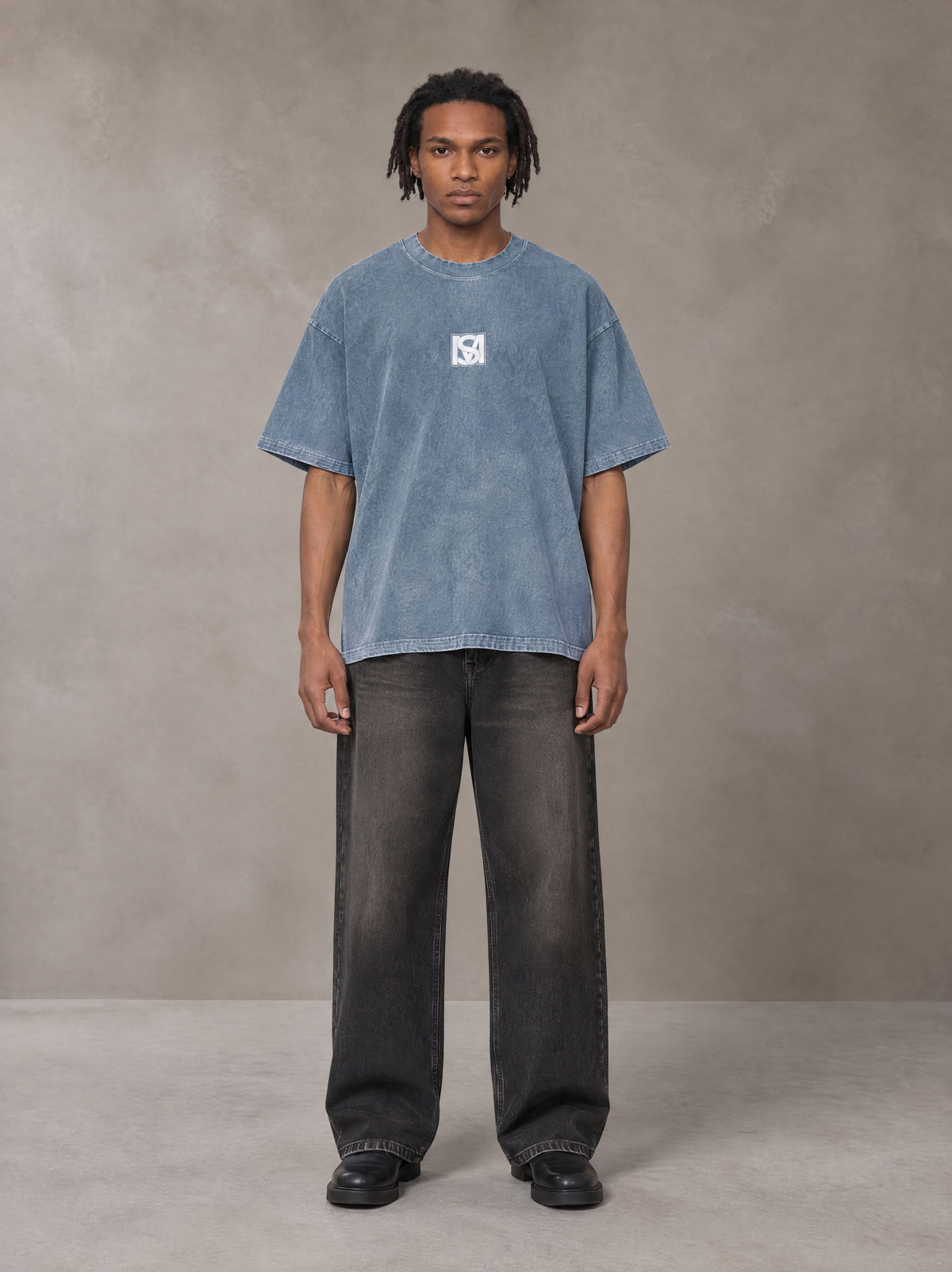 Model wearing the SM Acid Wash T-shirt in Washed Blue Jean, front view.