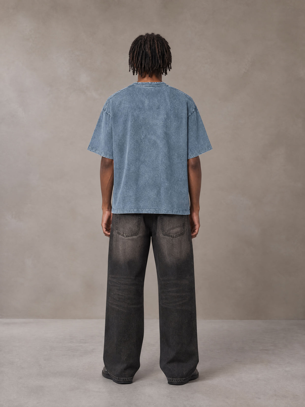 Model wearing the SM Acid Wash T-shirt in Washed Blue Jean, rear view.