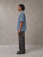 Model wearing the SM Acid Wash T-shirt in Washed Blue Jean, side profile.
