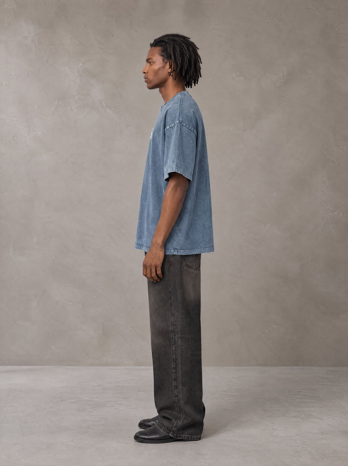 Model wearing the SM Acid Wash T-shirt in Washed Blue Jean, side profile.