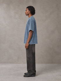 Model wearing the SM Acid Wash T-shirt in Washed Blue Jean, side profile.