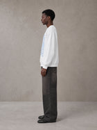 Model wearing the SM Baroque Bloom Sweatshirt in Lucent White, side profile.
