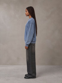 Model wearing the SM Denim Wash Sweatshirt in Chambray, side profile.