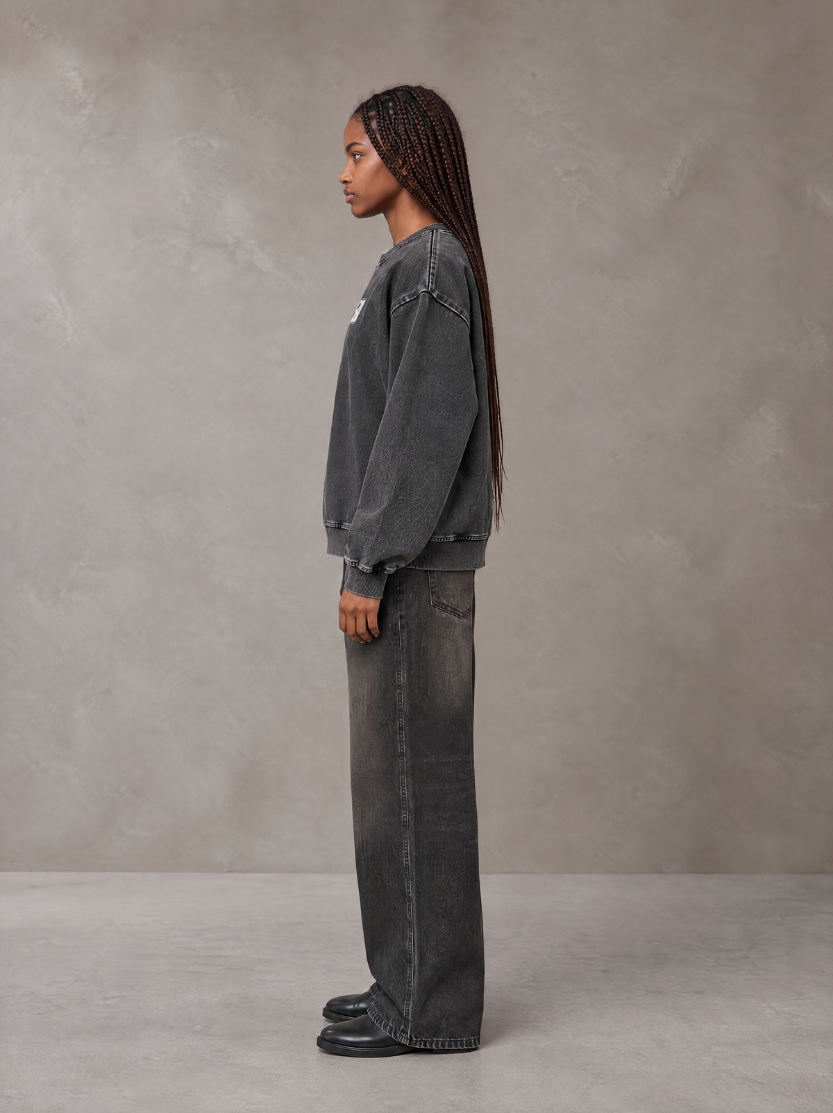 Model wearing the SM Denim Wash Sweatshirt in Midnight Black, side profile.