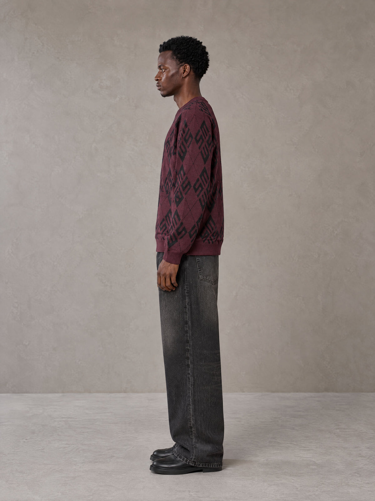 Model wearing the SM Argyle Jacquard Knitted Sweatshirt in Burgundy, side profile.
