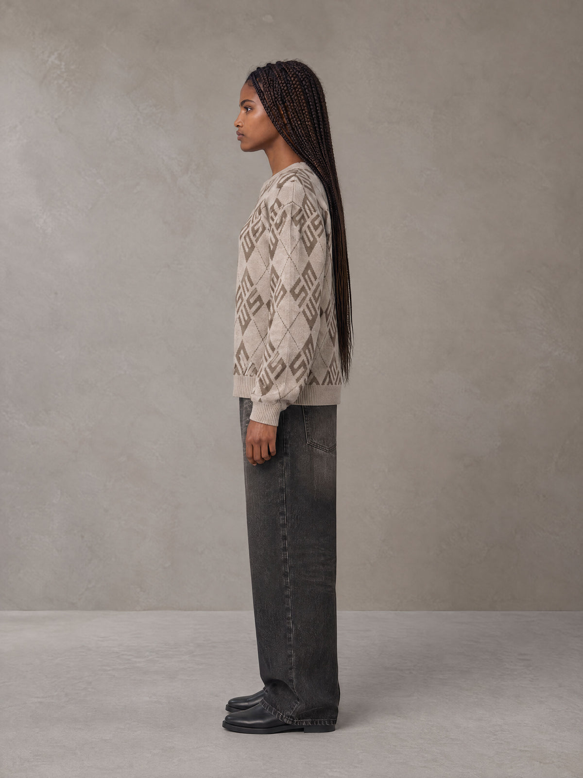 Model wearing the SM Argyle Jacquard Knitted Sweatshirt in Fine Sand, side profile.