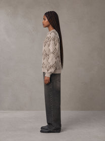 Model wearing the SM Argyle Jacquard Knitted Sweatshirt in Fine Sand, side profile.