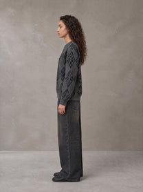 Model wearing the SM Argyle Jacquard Knitted Sweatshirt in Deep Charcoal, side profile.