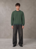 Model wearing the SM Jacquard Knitted Sweatshirt in Dark Green, front view.
