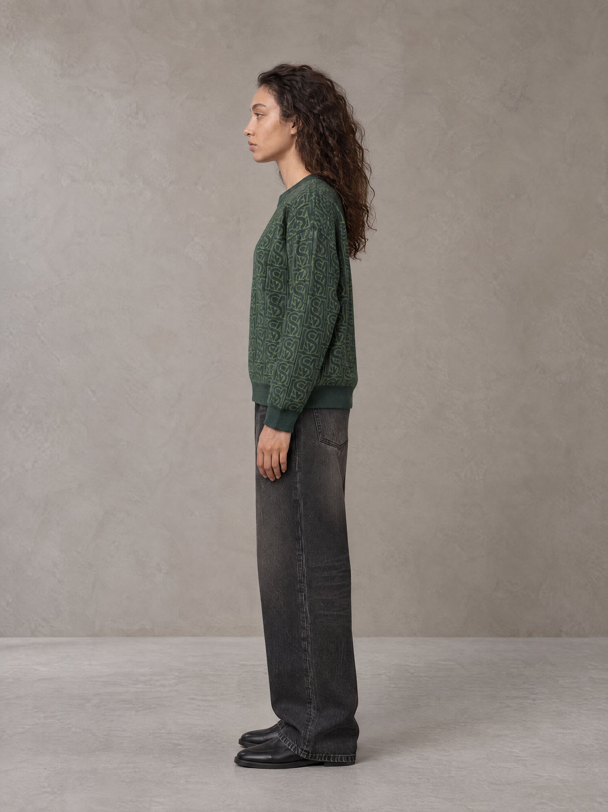 Model wearing the SM Jacquard Knitted Sweatshirt in Dark Green, side profile.