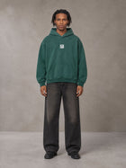 Model wearing the SM Monkey Wash Hoodie in Alpine Green, front view.